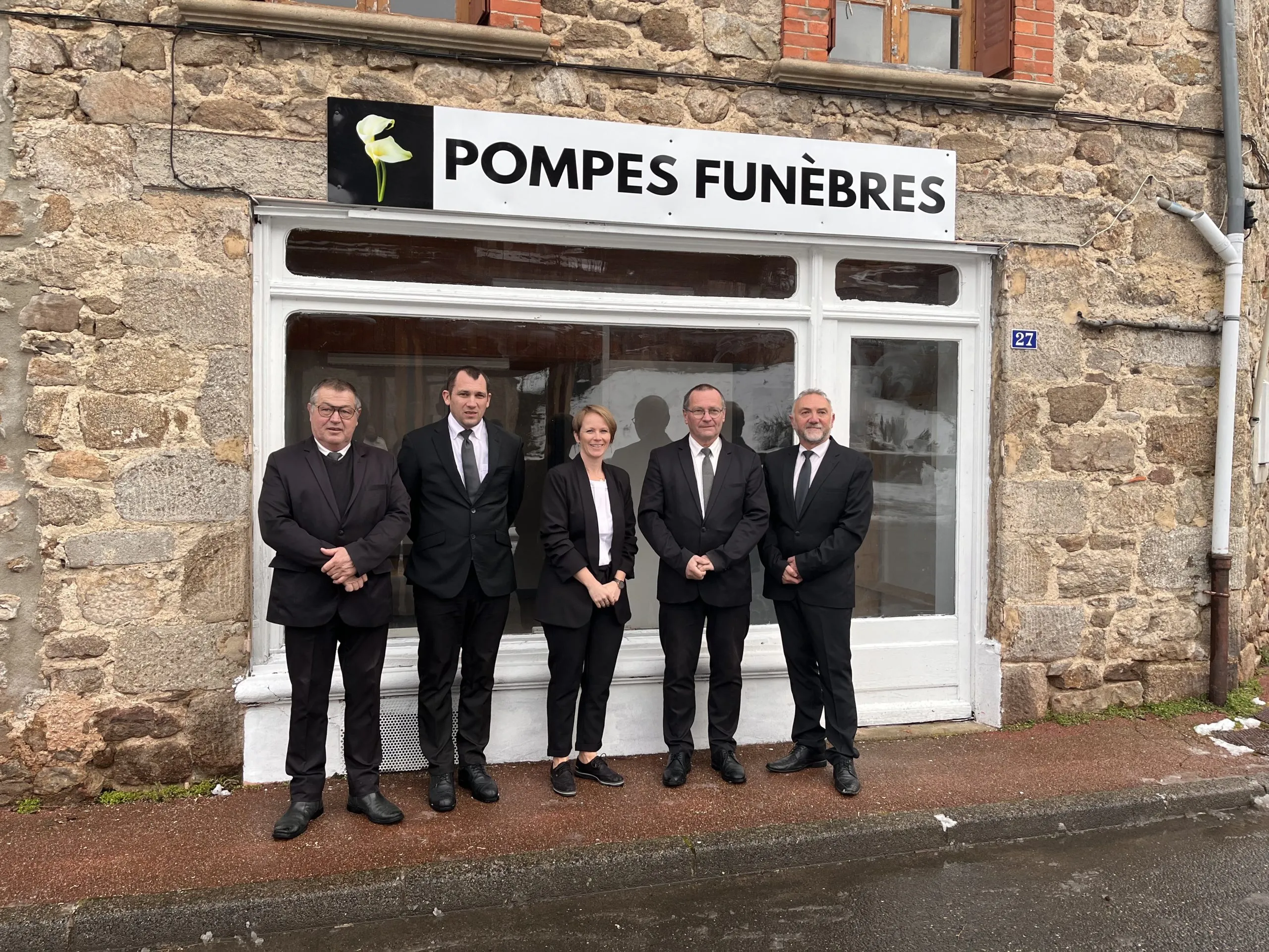 L'équipe des pompes funèbres pose devant la devanture en pierre de leur agence.